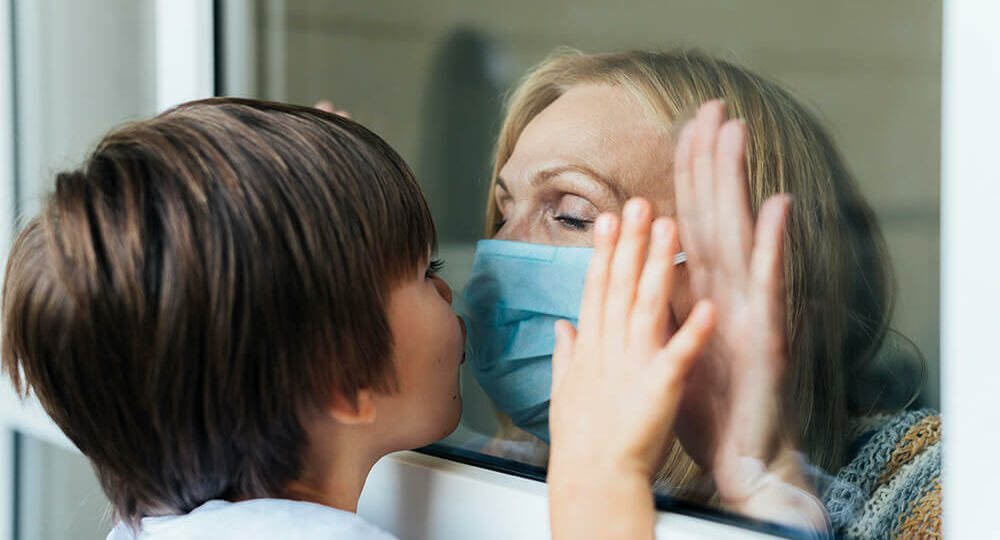 woman-with-medical-mask-kissing-nephew-through-the-window-in-quarantine-2
